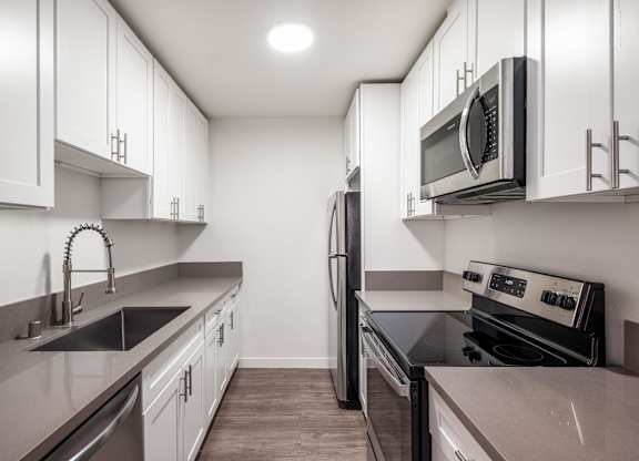 A modern kitchen with a stainless steel refrigerator and oven at Menlo Terrace Apartments, Los Angeles, CA, 90006