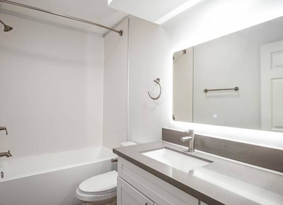 A white bathroom with a toilet, sink, and bathtub at Menlo Terrace Apartments, Los Angeles, 90006