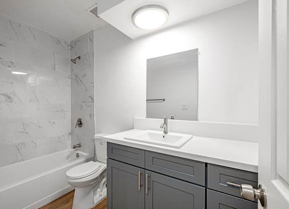 A bathroom with a marble tile wall and a white counter at Menlo Terrace Apartments, Los Angeles