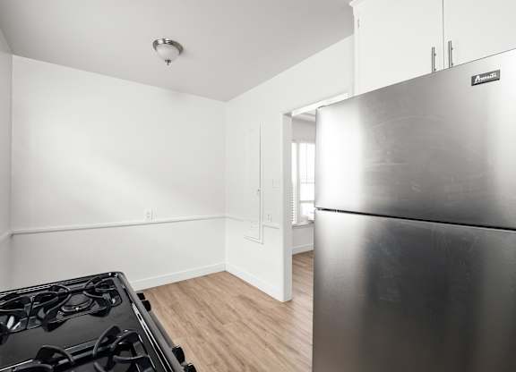 A modern kitchen with a stainless steel refrigerator and a black gas stove.at Normandie Grove, Los Angeles, CA 90004 