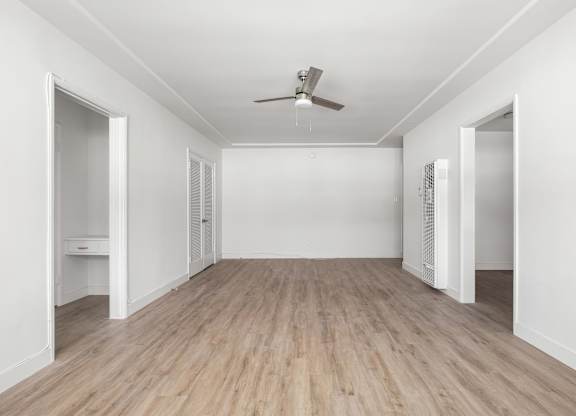 A room with a ceiling fan and light, and a wooden floor.at Normandie Grove, Los Angeles California 