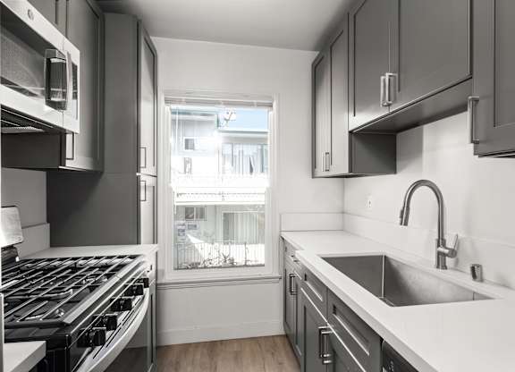 A modern kitchen with a stove top oven and a sink.at Normandie Groves, California 