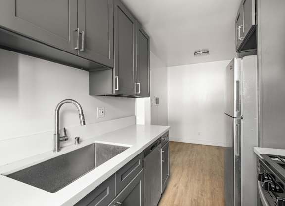 A modern kitchen with a stainless steel sink and refrigerator.at Normandie Grove, California, 90004