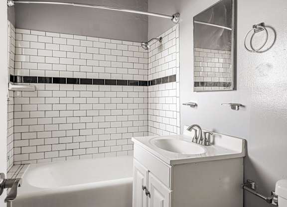 A white bathroom with a black and white tiled wall at Normandie Summit Apartments, Los Angeles, California
