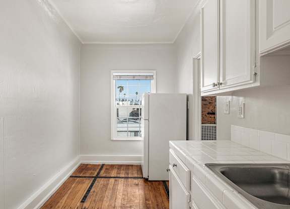 A kitchen with white cabinets and a window overlooking a cityscape at Normandie Summit Apartments, California 90004