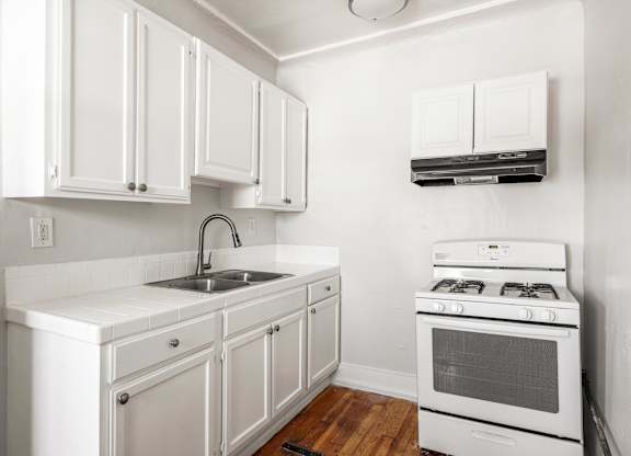 A white kitchen with a stove, sink, and cabinets at Normandie Summit Apartments, Los Angeles, 90004