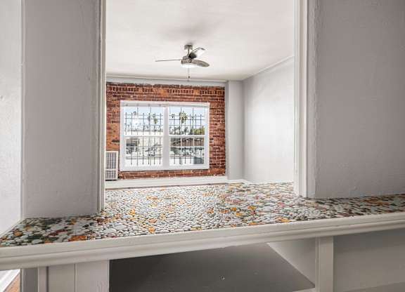 A room with a brick wall and a ceiling fan at Normandie Summit Apartments, Los Angeles