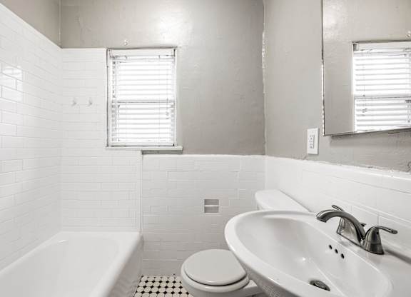 A white bathroom with a toilet, sink, and bathtub at Normandie Summit Apartments, Los Angeles, CA, 90004