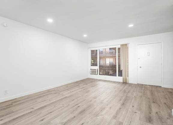 A room with wooden flooring and white walls.at Palms at Menlo, Los Angeles, 90006 