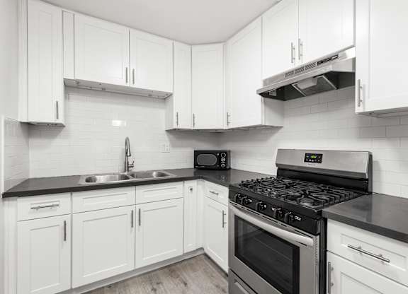 A kitchen with white cabinets and black countertops.at Palms at Menlo, Los Angeles California 