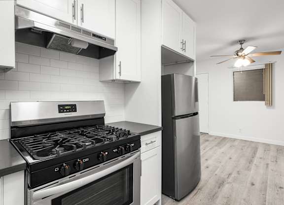 A modern kitchen with a stainless steel gas stove and a refrigerator.at Palms at Menlo, Los Angeles, CA 90006 
