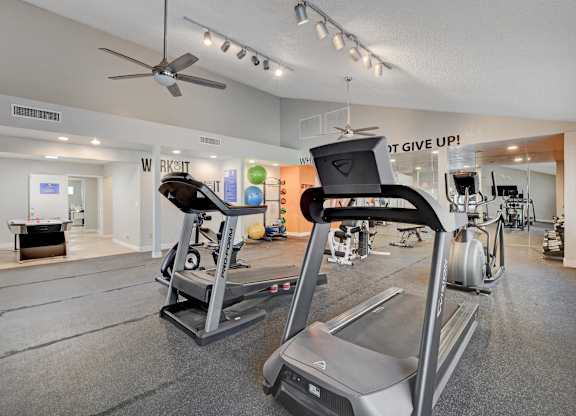 A gym with a variety of equipment including treadmills and weights.