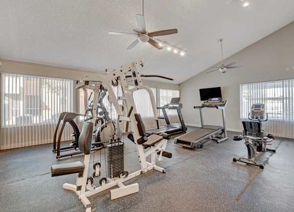 A home gym with a variety of equipment including a treadmill, weights, and a bench press.