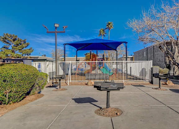 A playground with a blue canopy and a swing set.