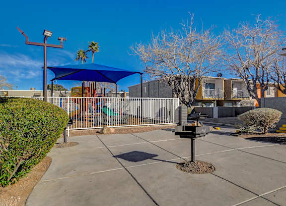 A playground with a blue canopy and a swing set.