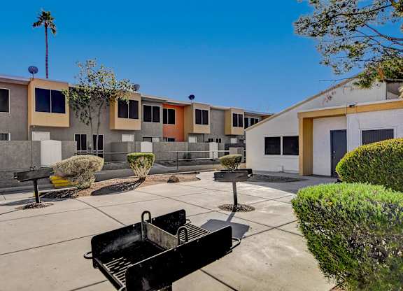 A black grill is in the middle of a concrete patio.