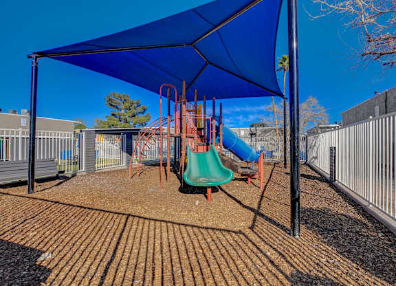 A playground with a blue canopy and a green slide.