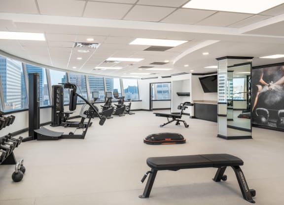 a large fitness room with exercise equipment and a large window overlooking the city at Vision on Lombard, Baltimore, MD 21201