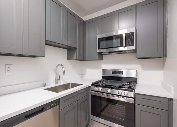 A kitchen with a stove, sink, and microwave at Westmore Manor Apartments, California