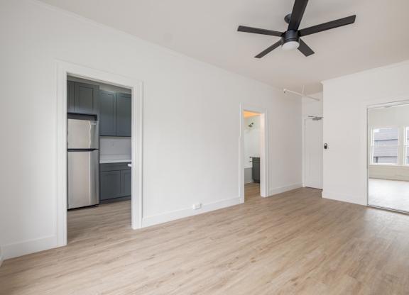 A spacious room with a ceiling fan and wooden flooring at Westmore Manor Apartments, Los Angeles