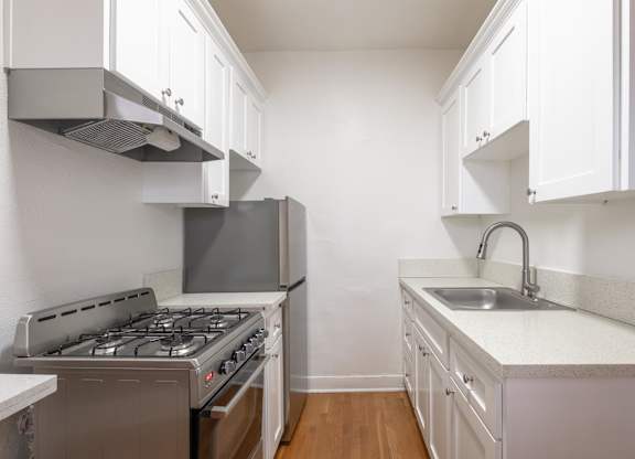 A kitchen with a stove, sink, and cabinets at Westmore Manor Apartments, Los Angeles, CA