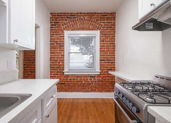 A kitchen with a brick wall and a stove top oven at Westmore Manor Apartments, Los Angeles, CA