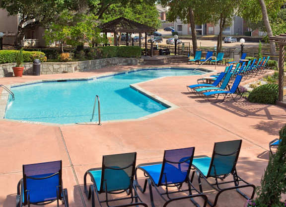 Swimming Pool Area With Shaded Chairs at Foxborough Apartments, Irving