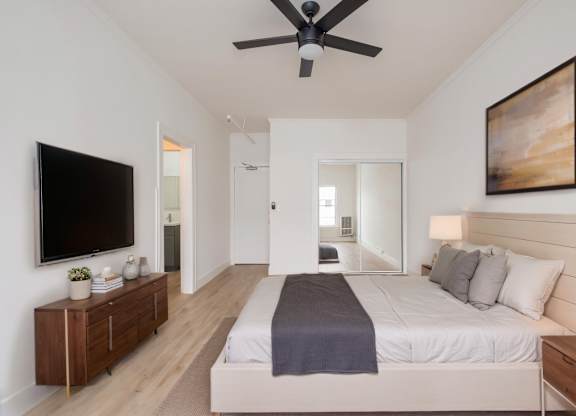 A bedroom with a bed, a ceiling fan, and a painting on the wall at Westmore Manor Apartments, Los Angeles, 90020