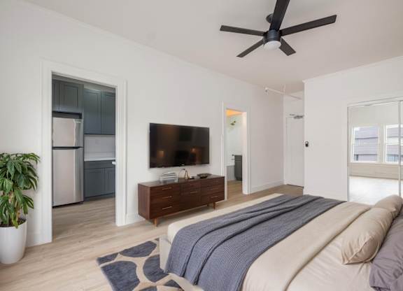 A bedroom with a bed, a television, and a plant at Westmore Manor Apartments, Los Angeles, CA