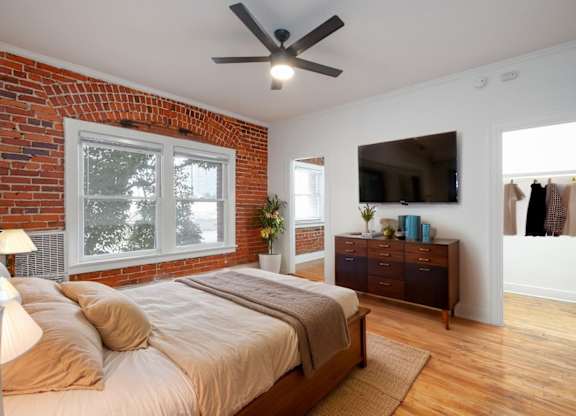 A bedroom with a brick wall and a large bed at Westmore Manor Apartments, California, 90020