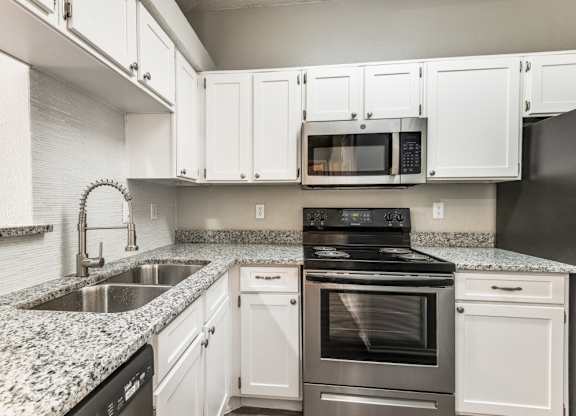 a kitchen with white cabinets and granite countertops at Foxborough Apartments, Irving, Texas
