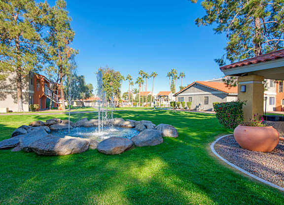 A garden with a fountain and a large pot.