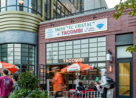 people walking past a taco restaurant in front of a building at The Grace and Reva, Arlington, 22202