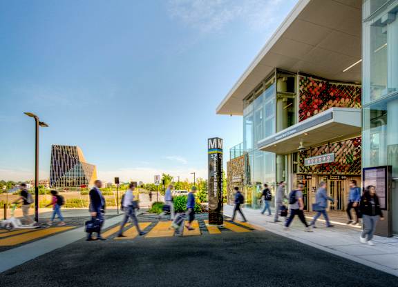 A group of people are walking on a sidewalk in front of a building.