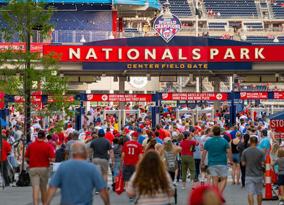 A large crowd of people are walking towards the entrance of Nationals Park.