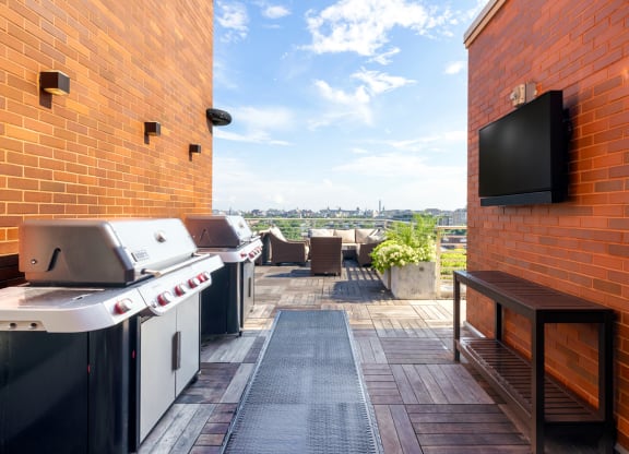a patio with two barbecue grills and a flat screen tv