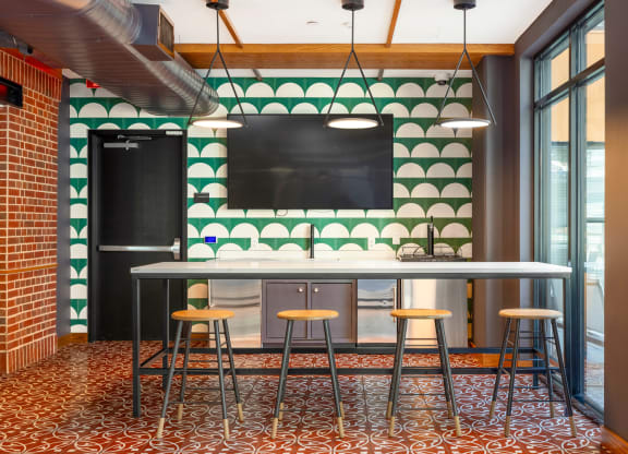a bar with four stools in front of a green and white tile wall