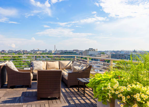 a roof deck with couches and chairs and a view of the city