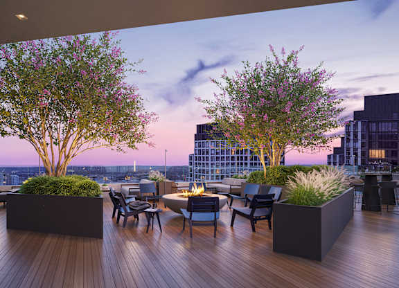 A wooden deck with a table and chairs and two trees.