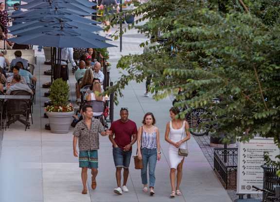 A group of people walking down a sidewalk in a city.