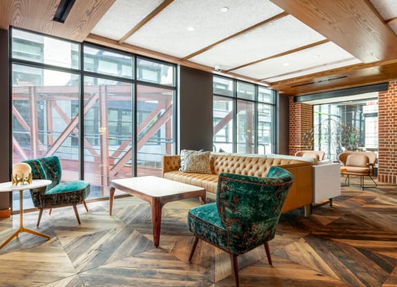 a living room with a couch and chairs and large windows