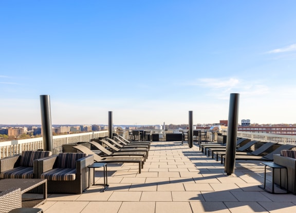 a roof top lounge area with chairs and tables and a view of the city