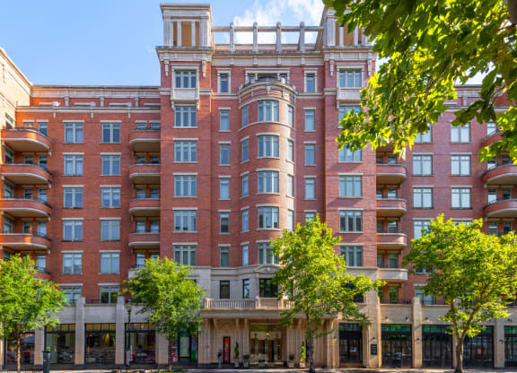 a photo of a large red brick building with balconies and trees in front of it