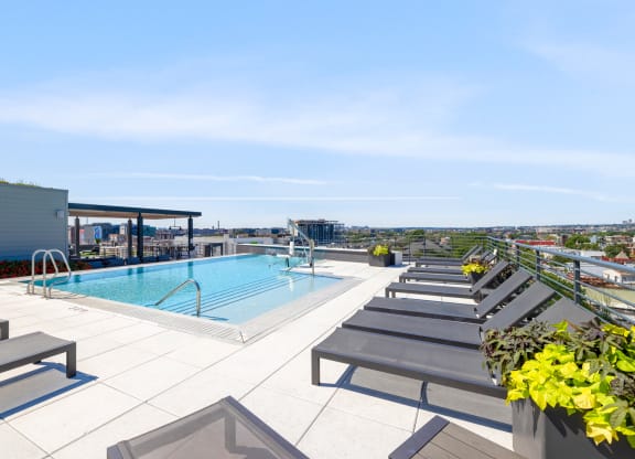 a swimming pool on the rooftop of a building with a city in the background