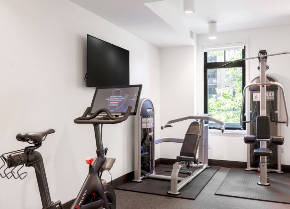 a gym with exercise equipment and a flat screen tv in a 555 waverly unit
