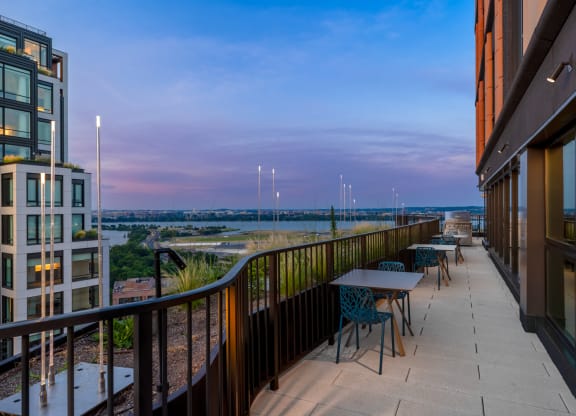 a balcony with tables and chairs and a view of a city at dusk at The Grace and Reva, Virginia