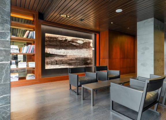 a lounge area with chairs and tables and a painting on the wall