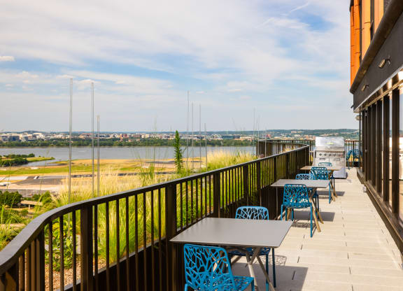 a balcony with tables and chairs and a view of a river at The Grace and Reva, Arlington