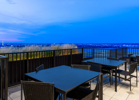 a terrace with tables and chairs overlooking the ocean and the city at night at The Grace and Reva, Arlington, Virginia
