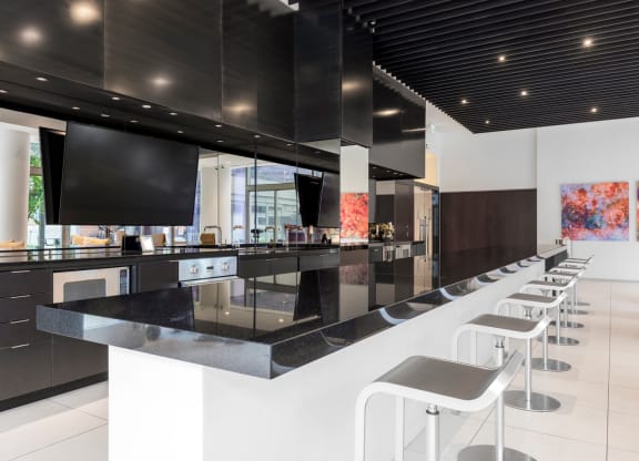 the kitchen has a bar with stools and a large tv